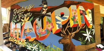 A colorful mural proclaims: Greetings from Maupin. The background and letter interiors are adorned with renditions of local plants and wildlife.
