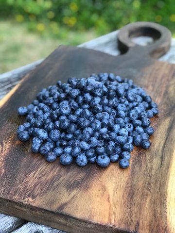 Blueberries piled on a wooden cutting board.