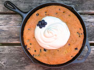 Blueberry baked good in a cast iron skillet on a table.