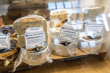 A selection of blue cheeses are arranged for display in the glass retail case.