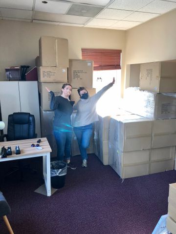 WVVA staff, Katie McFall and Tori Middelstadt, while wearing masks due to COVID-19 stand next to multiple boxes, stacked taller than they are, filled with various sizes of almost 800 life jackets. 