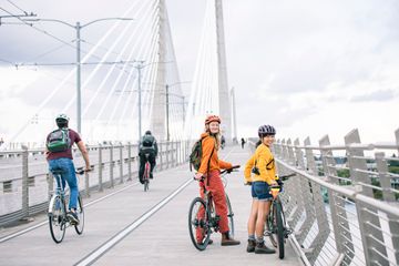 Women biking on the Tilikum Crossing bridge over the Willamette River in Portland, OR.
