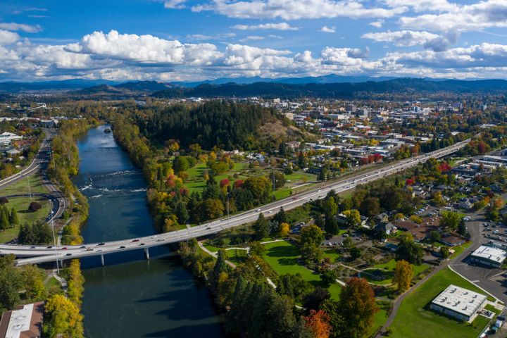 An aerial photo of the city of Eugene and a river intersecting a highway in the fall.